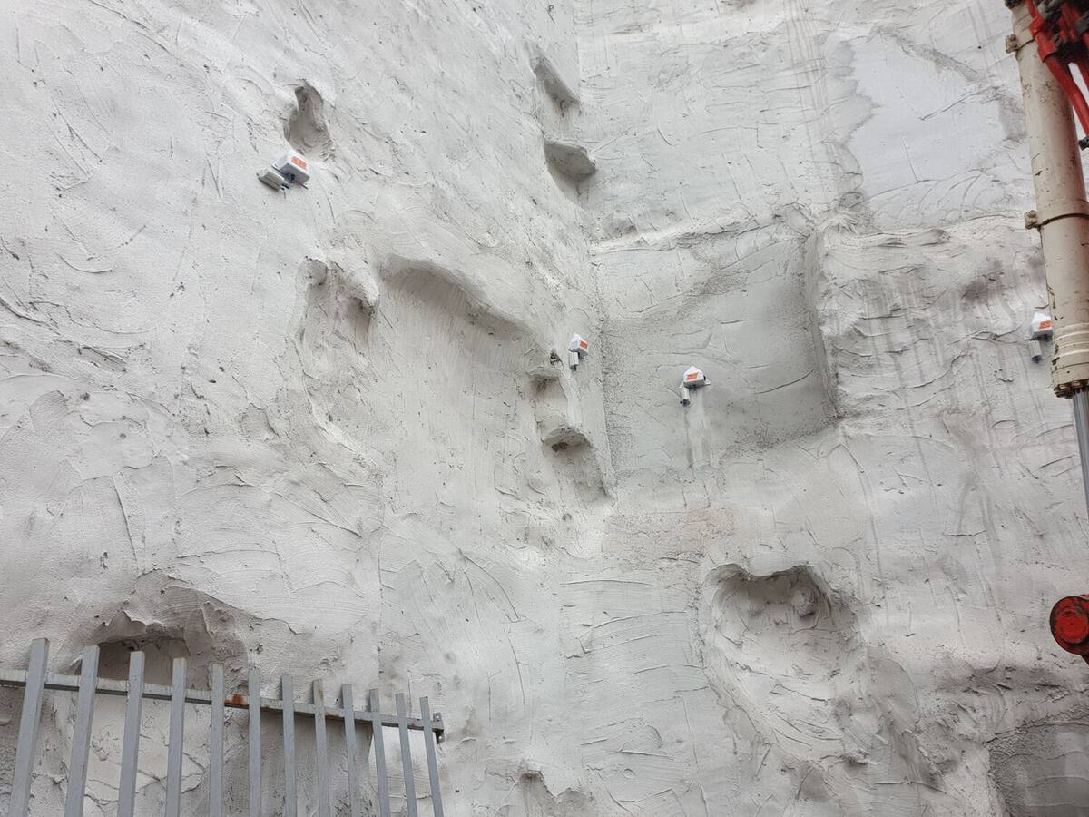 Mur en béton projeté équipé de cibles de mesure blanches et oranges destinées au suivi topographique des déplacements.